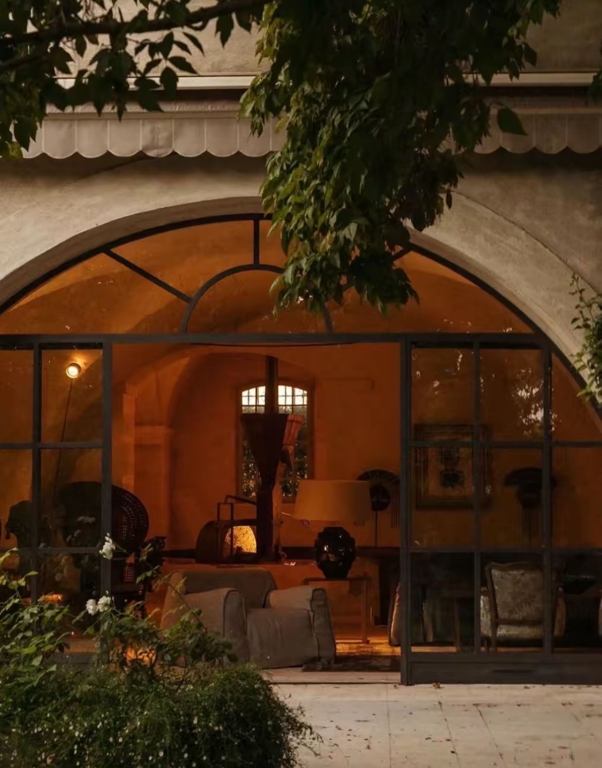 A warmly lit restaurant framed by greenery